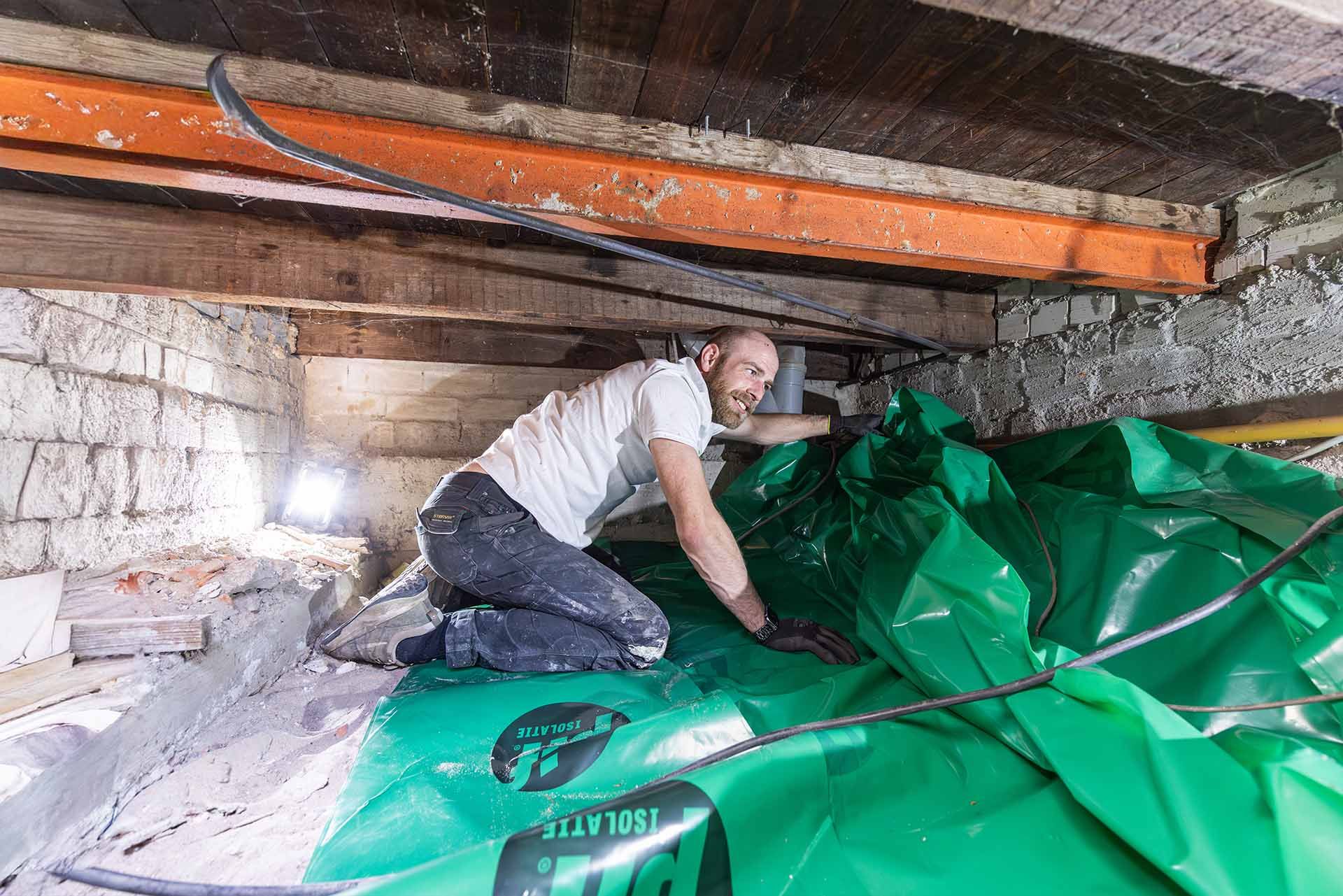 Bodemfolie wordt aangebracht in een lage kruipruimte voor bodemisolatie